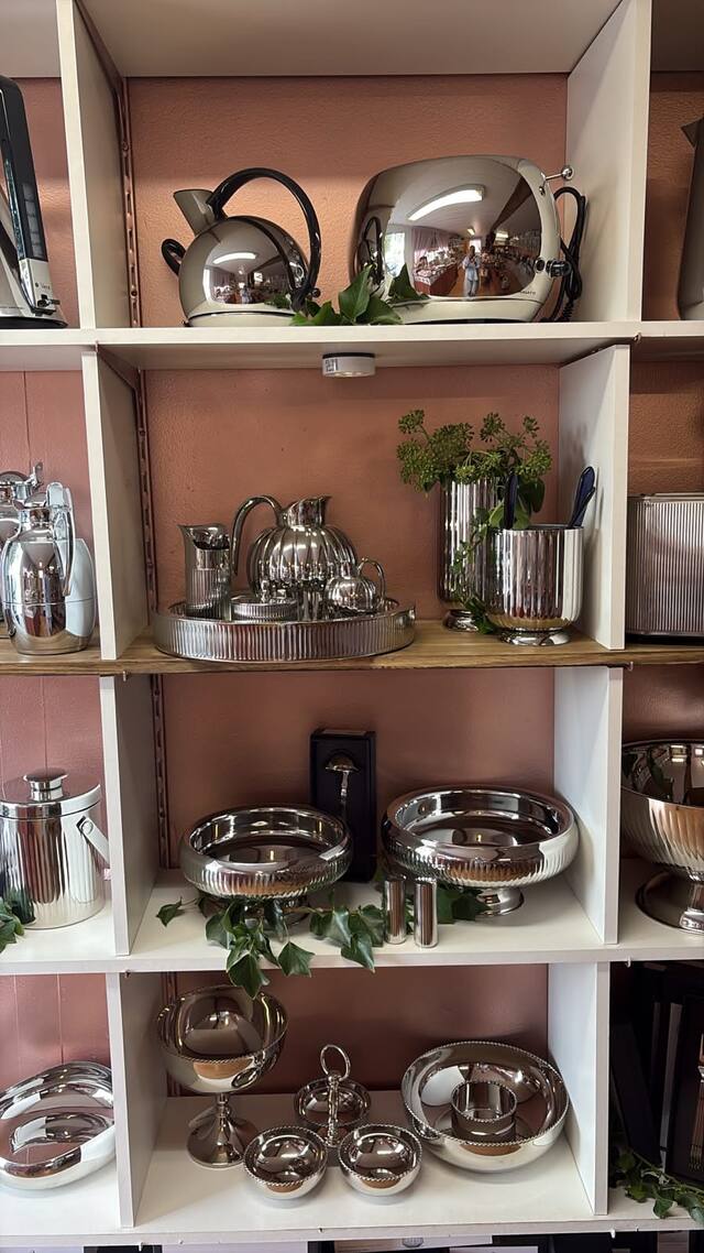 Bouilloire et grille-pain chromés Casa Bugatti sur une étagère, le grille-pain reflète l’intérieur de la boutique.