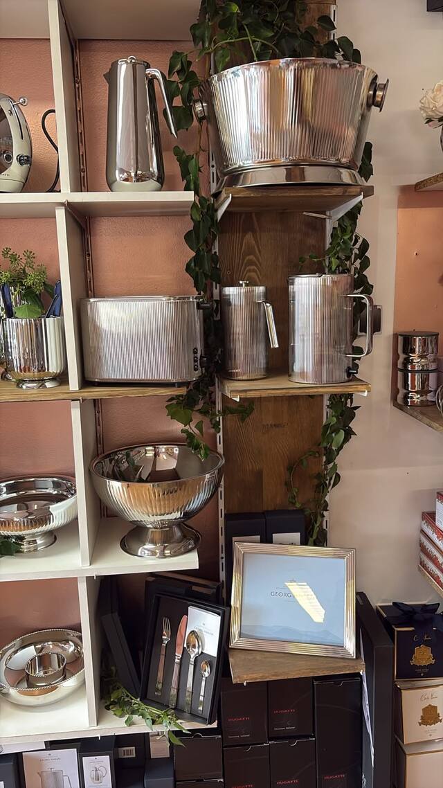 Seau à champagne, cafetières et coupe en acier cannelé sur des planches de bois, lierre retombant, coffrets Côte Noire en bas à droite.