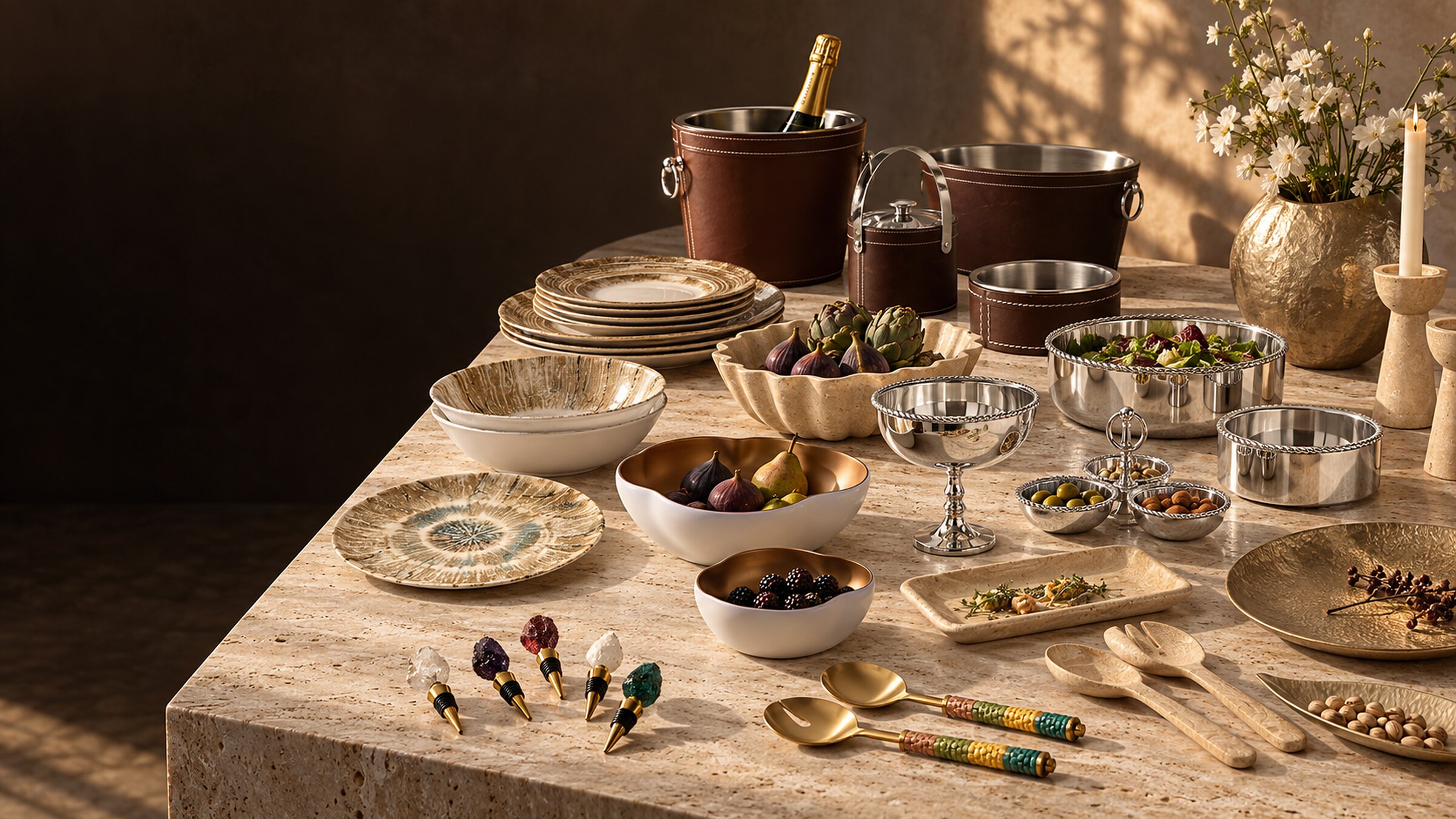 Nouveautés Aulica : seaux en simili cuir, vaisselle écorce, pièces effet travertin, inox torsadé et aluminium sable sur une table en travertin
